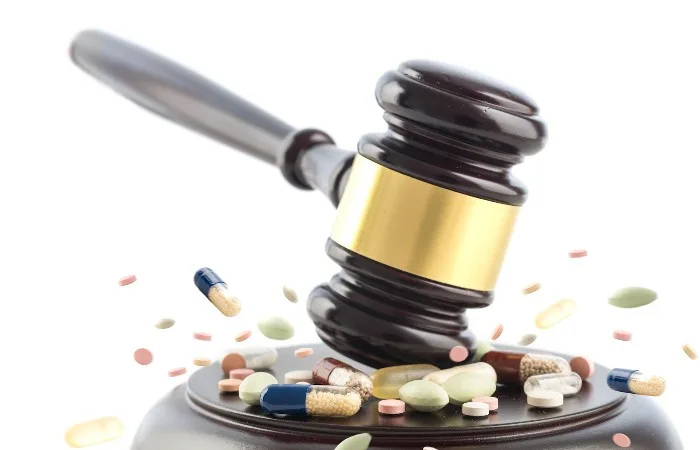 Gavel impacting pills, symbolizing legal influence on drug regulation.